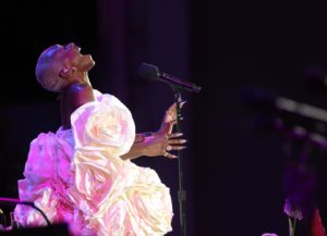Cynthia Erivo, resplendent in a gathered, white dress, throws her head back and sings.